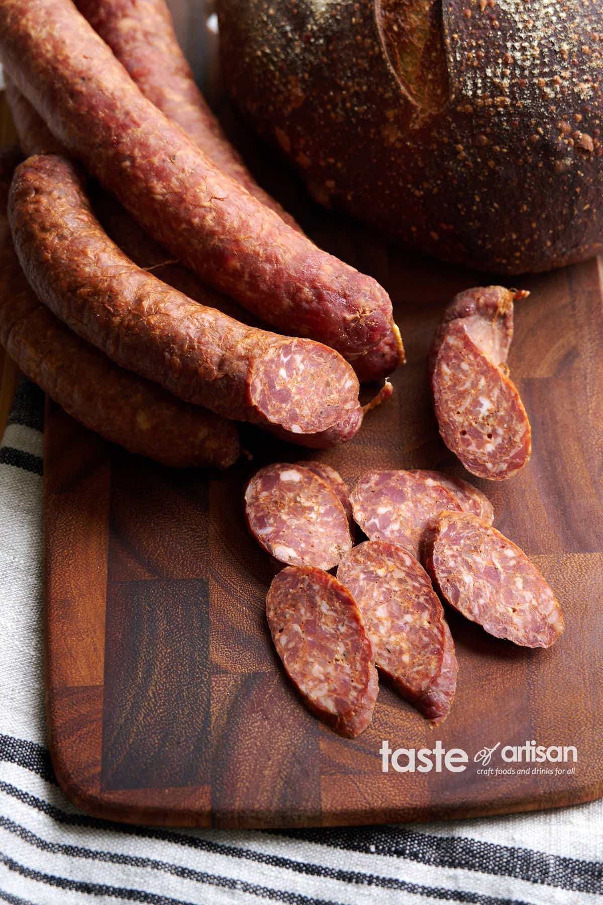 Sremska Smoked Sausage on a cutting board with a loaf of bread.