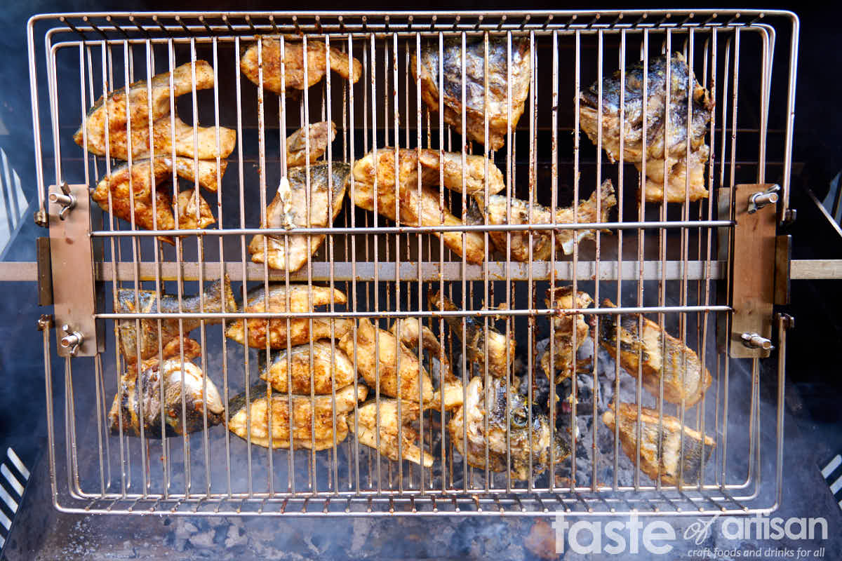 Cooking fish in a rotisserie in a flat basket.