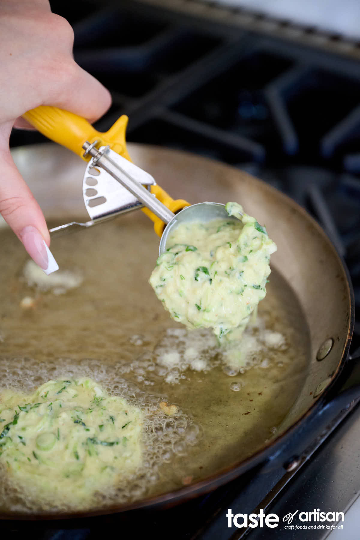 Dropping pancake batter into a pan with hot oil.