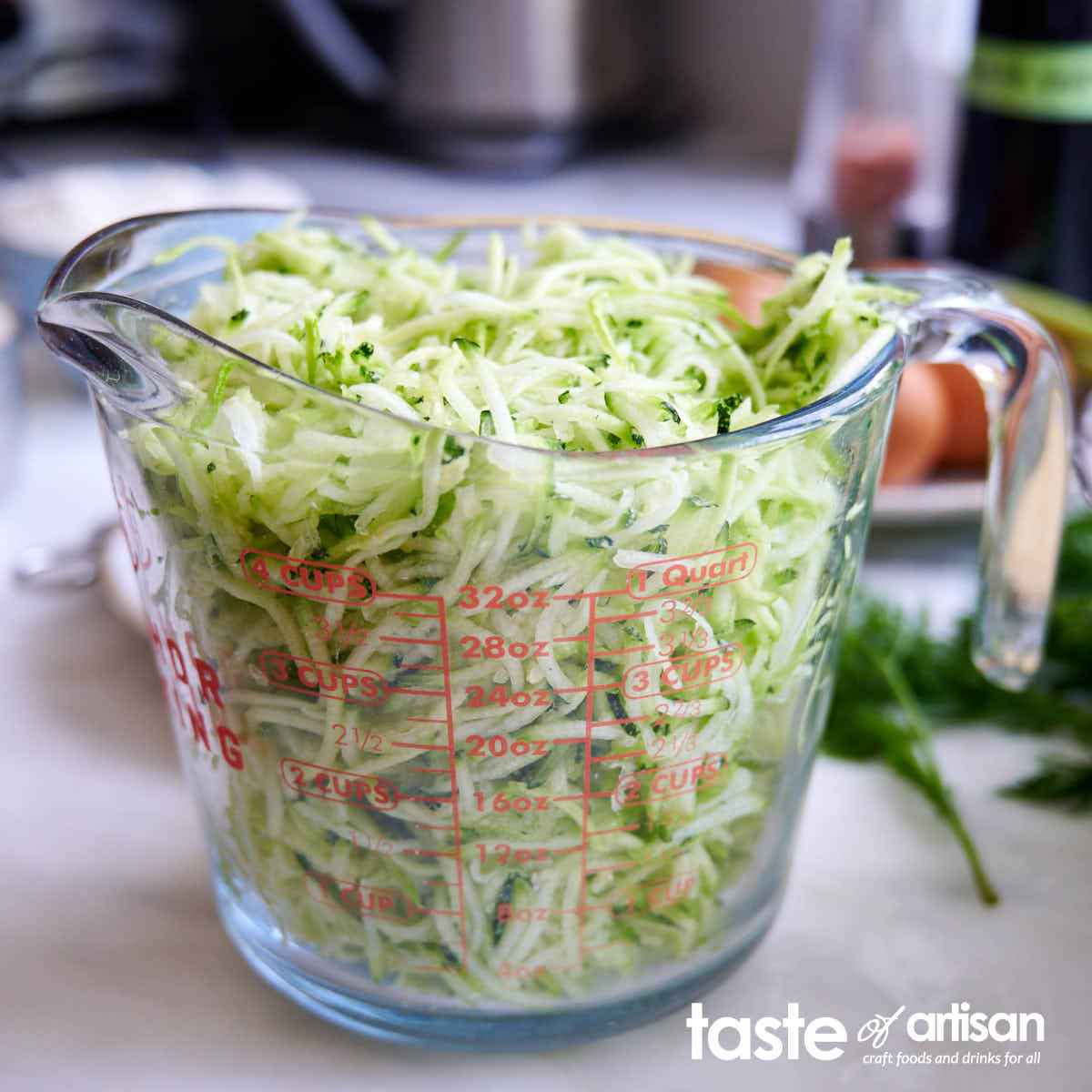 Squeezed shredded zucchini in a measuring cup.