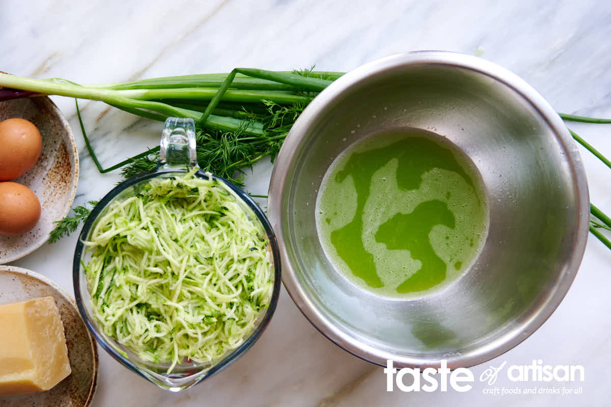 Shredded and squeezed zucchini in a bowl next to zucchini juice.
