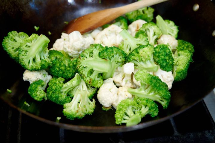 Roasting broccoli and cauliflower in a wok.